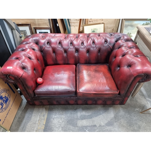 965 - Star Lot -A handsome oxblood leather Chesterfield sofa to seat two people. This striking love-seat s... 