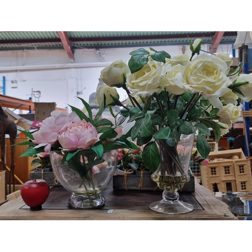 968 - Two heavy glass pedestal vases. Both presented with artificial flowers including white roses and pin... 