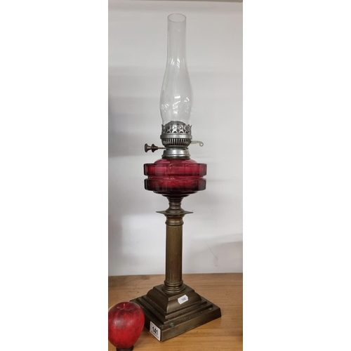 141 - A fabulous vintage oil lamp with a cranberry glass reservoir brass column base and glass chimney. Al... 