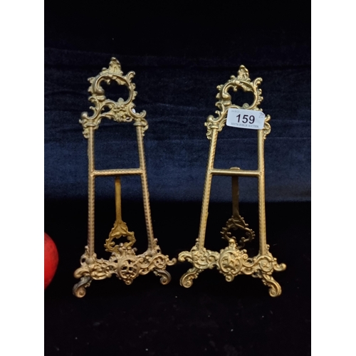 159 - A pair of brass neatly sized easel stands with ornate detail.