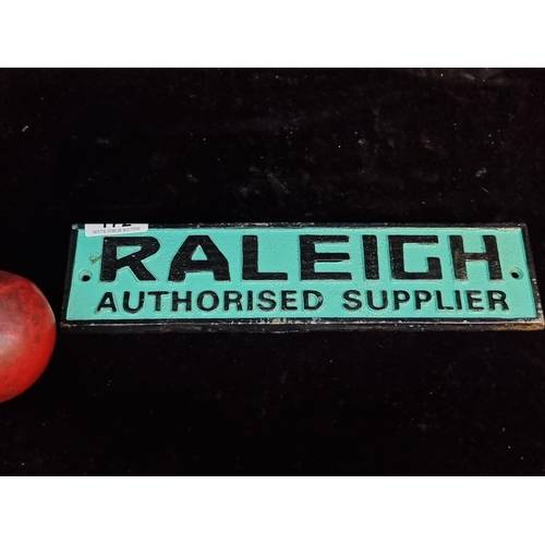 172 - A heavy cast metal advertising sign for Raleigh bikes on a bright turquoise ground.