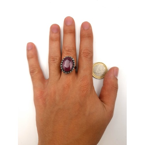 54 - A fabulous huge facet cut Ruby and diamond ring, set with an oval Diamond halo and a claw setting. S... 