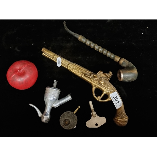 301 - Four items including an interesting rare antique pipe, a brass gun wall hanging, a syphon spout and ... 