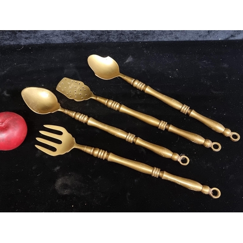 302 - Four brass serving utensils including spoons, a fork and a spatula.