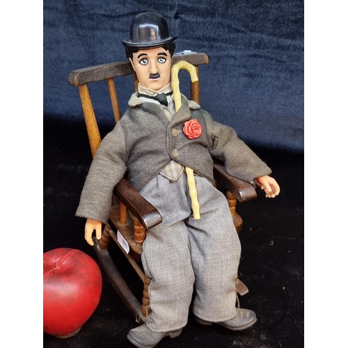 117 - A novelty doll of Charlie Chaplin with plastic and plush features. Accompanied by a neatly sized woo... 