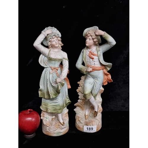 189 - A pair of ornate vintage bisque porcelain  figures of lady and gentleman in elegant garments with gi... 