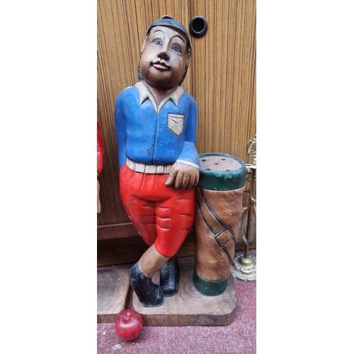 294 - A tall hand carved heavy free standing golfer statue, featuring characterful features, a golf bag, a... 