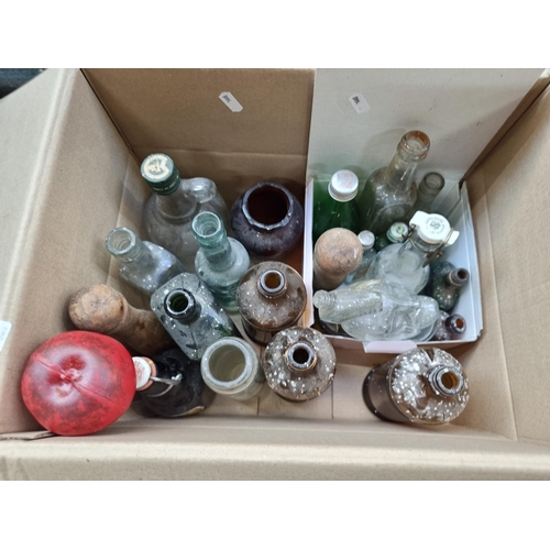 398 - A box containing 23 items including vintage glass bottles and a pair of vintage wooden bowling pins.