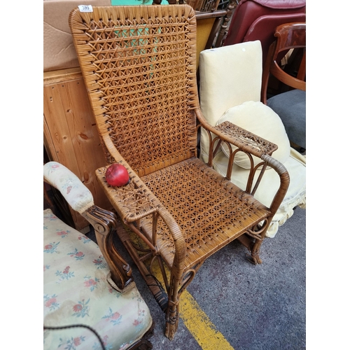 399 - A vintage wicker armchair with armrests curvilinear detail to base. Small partial loss to the arm.