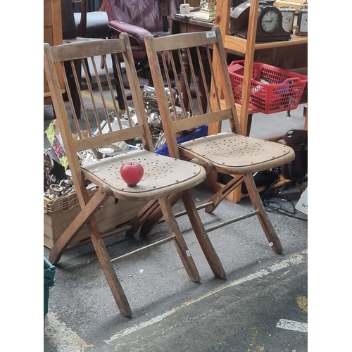 462 - A pair of vintage fold out wooden chairs manufactured by Arnotts Dublin, with spindle back and pierc... 