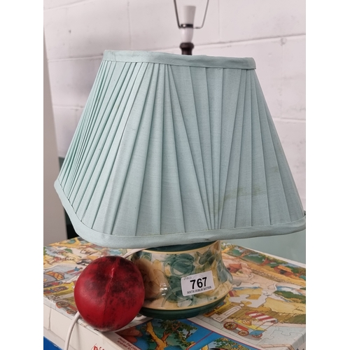 767 - A delicate Jersey Pottery ceramic lamp with accompanying blue shade. Complete with three pin plug.