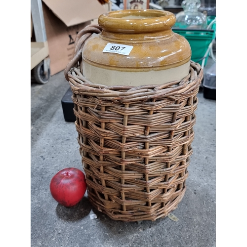 807 - A vintage stoneware jar held in a wicker basket with handle.   Provenance: from Palladian stately ho... 