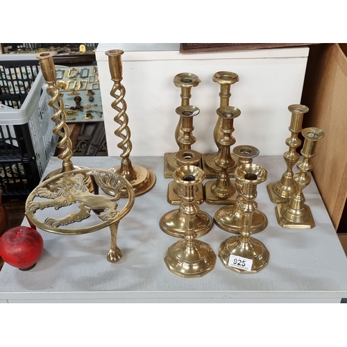 925 - Thirteen brass items including six pair of candle holders and a kettle trivet with a lion motif.