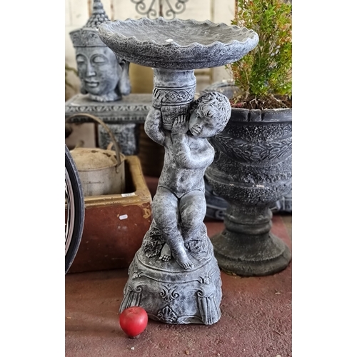 926 - An ornate reconstituted stone garden bird bath with a basin held on a stem in the form of a cherub. ... 