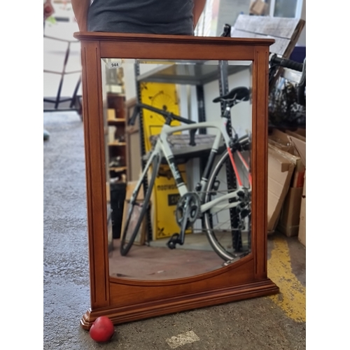 944 - A large wall mirror with bevelled glass housed in a wooden frame featuring fluted detailing. H90cm x... 