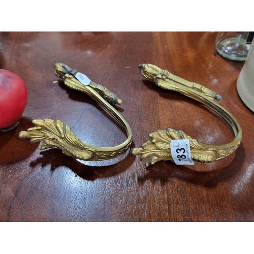 783 - A pair of elegant antique brass curtain tie back hooks.