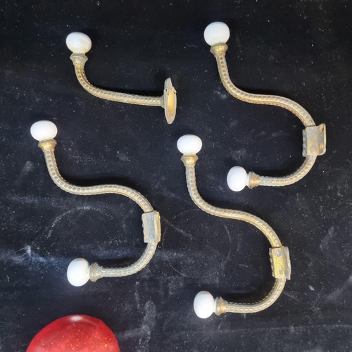 109 - Four matching brass coat hooks with ceramic ends