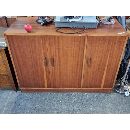 916 - A Mid-Century Modern cabinet with interior shelving and stylized handles. H81cm x L113cm x D48cm.