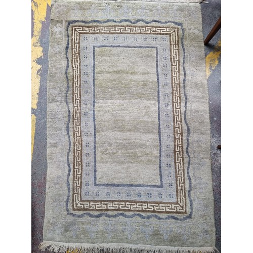 923 - A lovely handknotted wool rug with a deep pale in shades of sage green and grey. Featuring fleur-de-... 