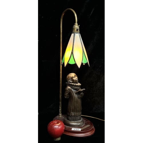 211 - A table lamp with coloured glass shade, brass stem with a base featuring a figure of a choir boy. Fi... 