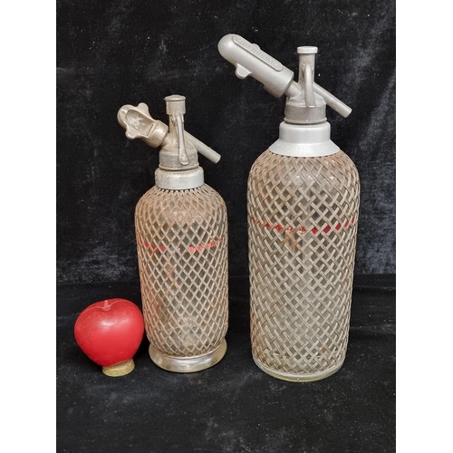 215 - A lovely duo of early 20th Century soda syphons covered in a metal mesh.