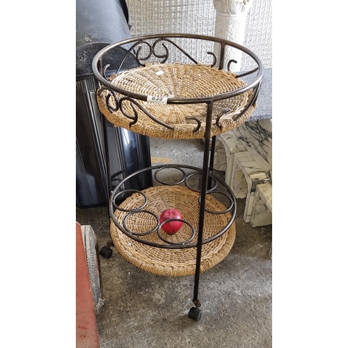 839 - A heavy charming bar cart with round wicker tiers and bottle stands. Held on three castors. H70cm