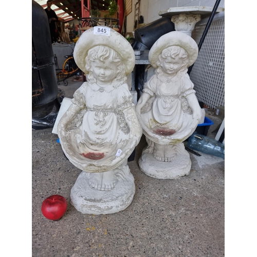 845 - An adorable pair of reconstituted stone garden bird baths in the form of girls holding up their skir... 