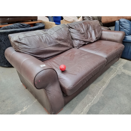 943 - A large three-seater brown leather sofa. A nice contemporary example in a cool tone with stitch deta... 