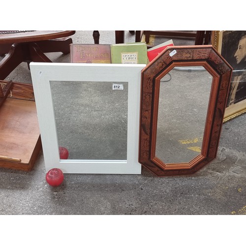 812 - Two wall mirrors including one in an ornate wooden frames with angled corners (H58cm x W33cm) and th... 