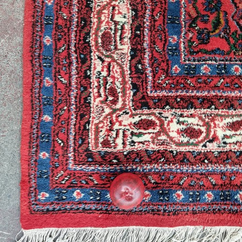 948 - Star Lot: A gorgeous hand knotted wool rug with a foliate motif in jewel tones of red and blue with ... 