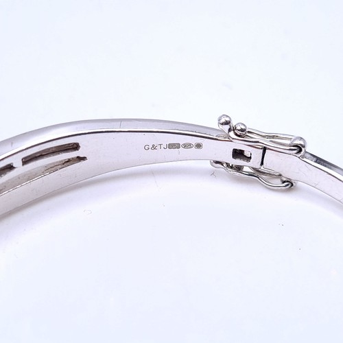 15 - A sterling silver bangle bracelet with attractive gem stone twist mount. Total weight 17 grams