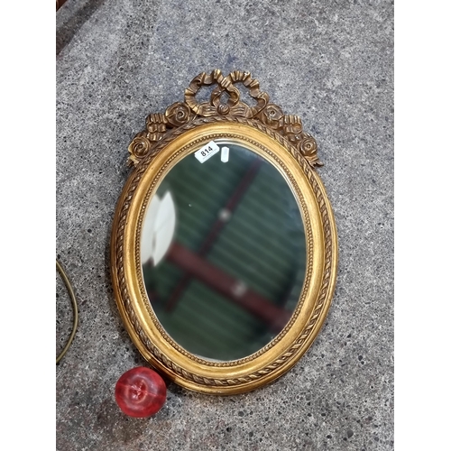 814 - A pretty vintage oval bevelled mirror housed in a Regency style gilded frame. H53cm x W37cm