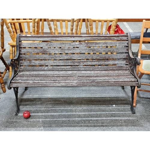 819 - A vintage cast metal three-seater garden bench with wooden panels and cast metal ends featuring foli... 