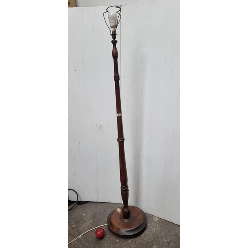 894 - A handsome vintage floor standing lamp with a turned stem, round base and three pronged plug. H173cm... 