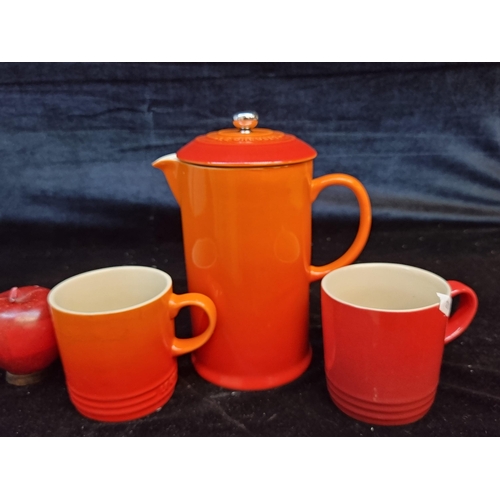 138 - Three Le Creuset items including a cafetière pot and two mugs in red and orange. Total RRP of approx... 