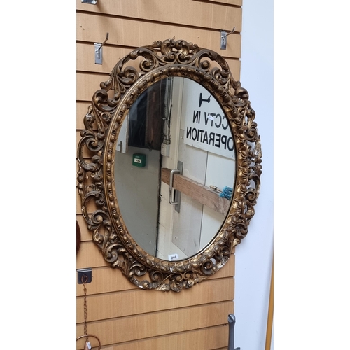 266 - Star Lot : A beautifully ornate Victorian oval mirror with scroll and foliate detailing to gilt mold... 