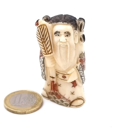 913 - An antique bone  unusual Netsuke figure, carved from bone and featuring an Asian gentleman donned in... 