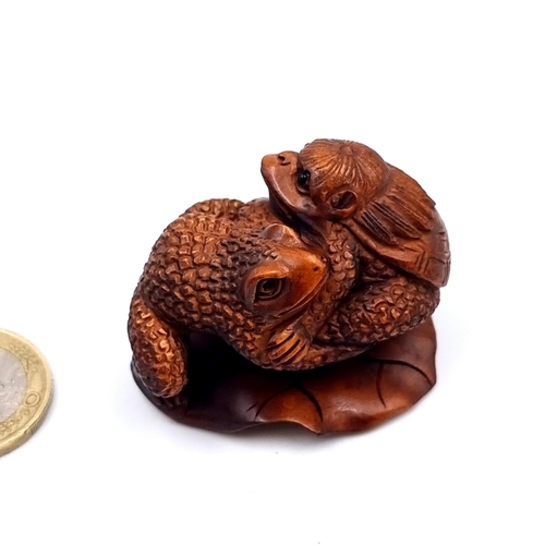 914 - An expertly carved boxwood Netsuke, featuring a river creature Kappa and a toad perched on a rock. W... 