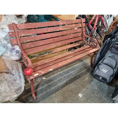 1039 - An antique garden bench with wooden slats and cast metal supports. In a red finish. Needs attention ... 