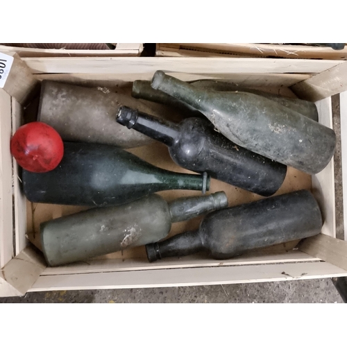 1088 - A crate containing seven 20th century glass bottles including green examples.