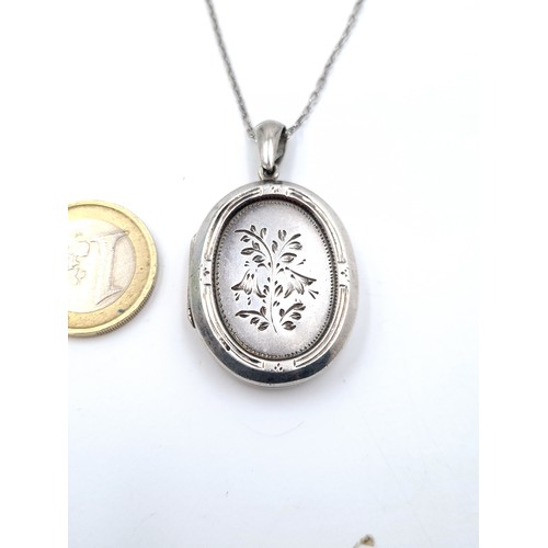 58 - A lovely sterling silver locket, set with a hinged accent and featuring pretty floral detail. Set wi... 