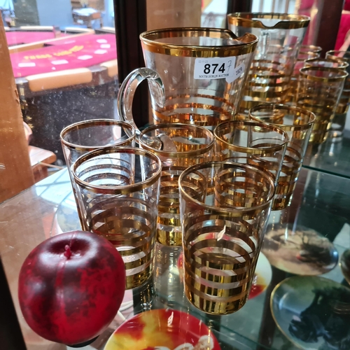 874 - Six stylish mid century drinking glass along with a large serving jug. All boasting gold gilt detail... 