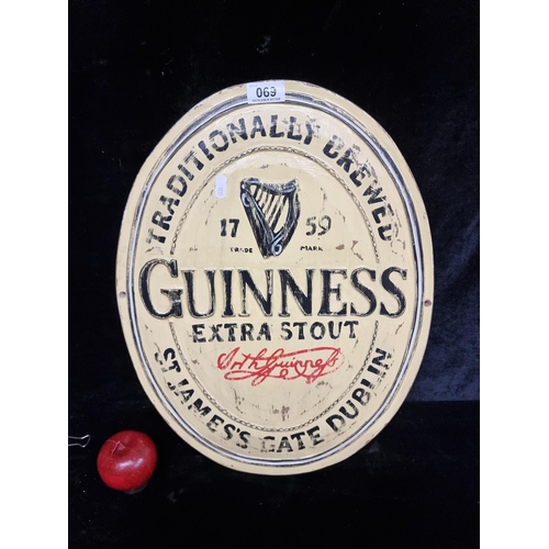 69 - An ovular wooden wall plaque advertising Guinness Extra Stout.