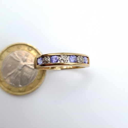 889 - Star Lot : A striking 9 carat gold wide banded Diamond and Tanzanite ring, featuring nicely set Diam... 