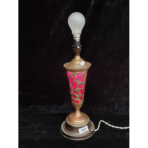 160 - A stunning Art Nouveau table lamp with pierced brass body containing a ruby glass shade. Both the ma... 