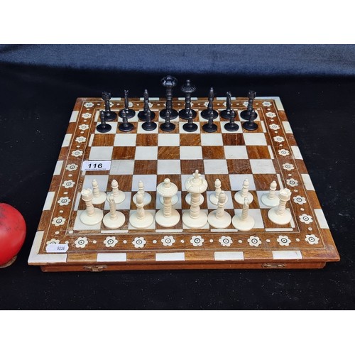 116 - An elegant full chess set comprising of a wooden board with a floral design and 32 playing pieces.