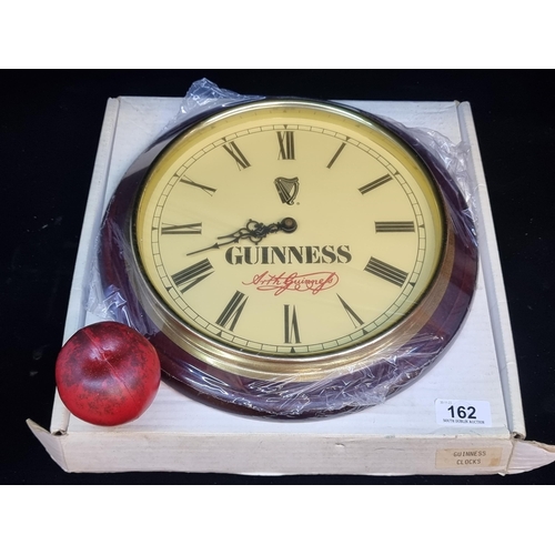 162 - A handsome vintage new old stock Guinness wall clock housed in round wooden frame with brass surroun... 