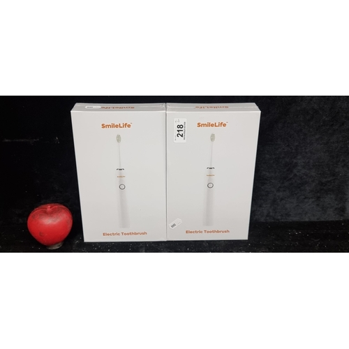 218 - Two brand new in box SmileLife electric toothbrushes. With additional heads and travel adapter