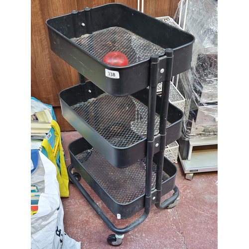 338 - A useful black metal tray organiser on castors. Could be used as a kitchen or DIY tool organiser.