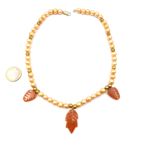 573 - A good quality natural pearl necklace set with gold bead detailing and carved carved agate leaf desi... 